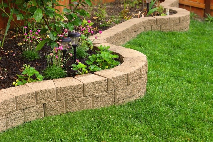 stone wall with perfect grass landscaping in garden with artificial grass